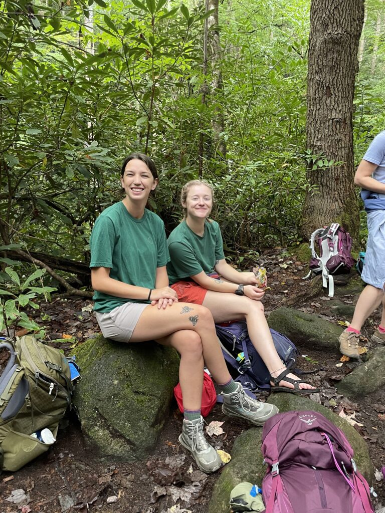 When you guide with us, lasting friendships are made. Guides sitting on a rock smiling.