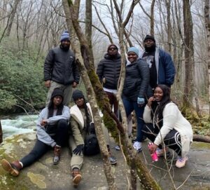 Family posing on a rock near a stream